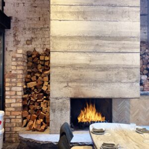 Corner Open wood fireplace in grey concrete surround in a restaurant interior